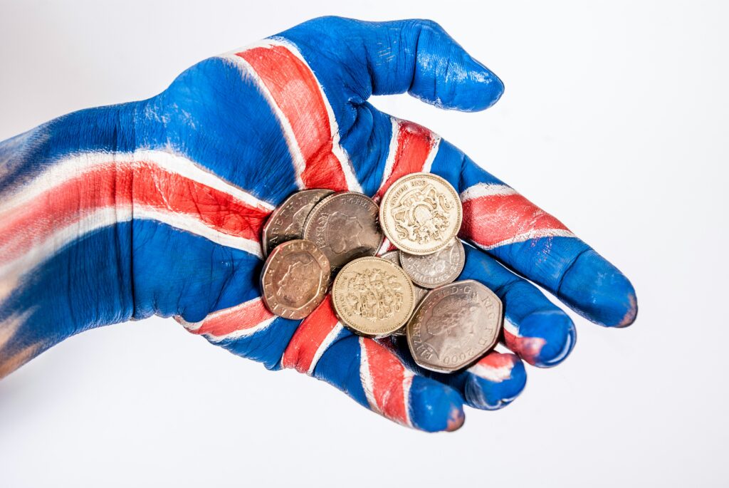 Coins in a hand painted with the British flag - moving to England